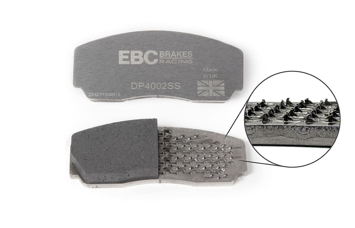 Pastilha de travão EBC em corte, com pormenor ampliado dos pinos metálicos que fixam o material de atrito à chapa de suporte