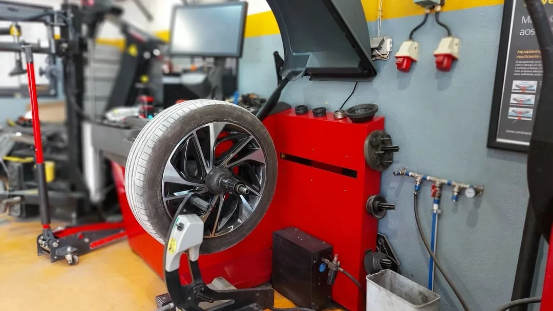 Roda montada numa máquina de equilibragem numa oficina, com o ecrã de leitura ao lado